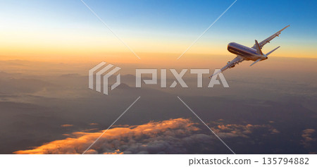 Airplane flying over mountains at sunset during golden hour Airplane flying over mountains at sunset during golden hour 135794882
