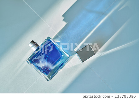 Blue perfume bottle on light background with shadow Blue perfume bottle on light background with shadow 135795380