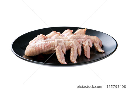 black plate with fresh chicken wings isolated on a white background. black plate with fresh chicken wings isolated on a white background. 135795408