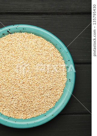 Organic white quinoa seeds in plate on black background. Organic white quinoa seeds in plate on black background. 135795430