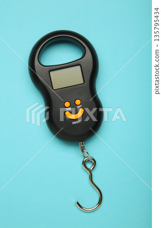 Small portable electronic scale on blue background. Vertical photo Small portable electronic scale on blue background. Vertical photo 135795434