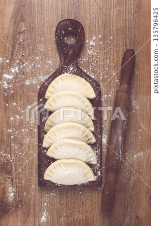 raw chebureks, mini, on a cutting board, wooden table, close-up, no people, 135796425