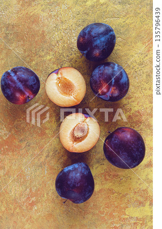 plums scattered on the table, fresh, top view, yellow-orange background, no people, 135796439