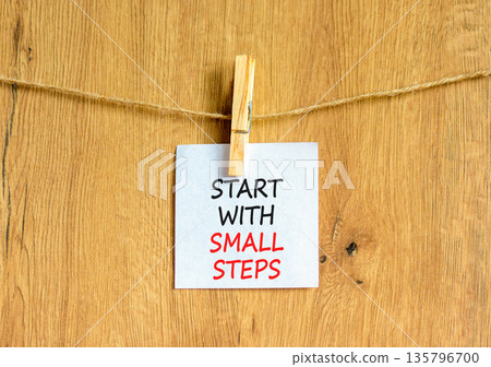 Start with small steps symbol. Concept words phrase Start with small steps on beautiful white paper on clothespin. Beautiful wooden background. Business Start with small steps concept. Copy space. Start with small steps symbol. Concept words phrase Start with small steps on beautiful white paper on clothespin. Beautiful wooden background. Business Start with small steps concept. Copy space. 135796700