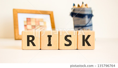 Risk symbol. Concept word Risk on beautiful wooden blocks. Beautiful picture frame and colored pencils. Beautiful white table white background. Business, lifestyle, support risk concept. Copy space. 135796764