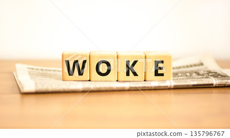 Woke question symbol. Concept word Woke question on beautiful wooden blocks on newspaper. Beautiful wooden table white background. Business, lifestyle, support and woke question concept. Copy space. Woke question symbol. Concept word Woke question on beautiful wooden blocks on newspaper. Beautiful wooden table white background. Business, lifestyle, support and woke question concept. Copy space. 135796767