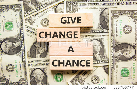 Give change a chance symbol. Concept words phrase Give change a chance on beautiful wooden blocks. Dollar bills. Beautiful dollar bills background. Business Give change a chance concept. Copy space. 135796777