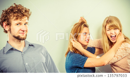 Aggressive mad women fighting over man. 135797033
