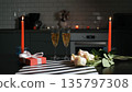 Champagne bubbles rise in glasses near roses and a gift box in a cozy kitchen. Valentines Day celebration 135797308