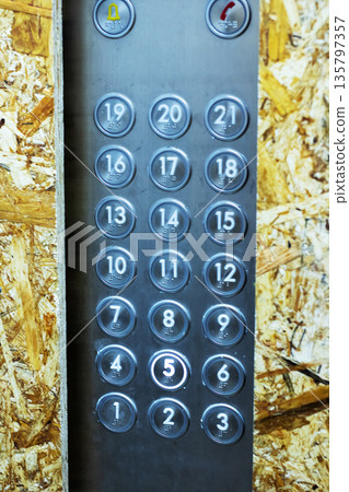 Close examination of scratched metal elevator buttons amid dusty renovation environment Close examination of scratched metal elevator buttons amid dusty renovation environment 135797357
