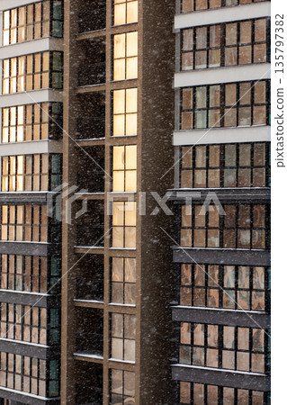 Metropolitan shopping complex with glowing windows surrounded by snow as day turns to night Metropolitan shopping complex with glowing windows surrounded by snow as day turns to night 135797382