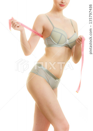 Woman in bra lingerie measuring her chest breasts. 135797486