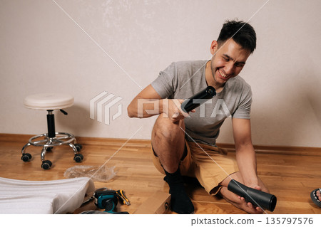 Cheerful young man assembling new office chair, sitting on floor, laughing and holding components, engaged in diy furniture construction in home environment. Cheerful young man assembling new office chair, sitting on floor, laughing and holding components, engaged in diy furniture construction in home environment. 135797576