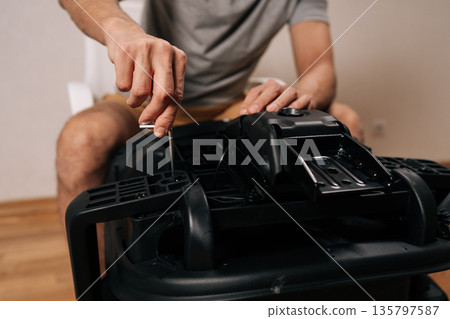 Male hands assembling new office chair, using allen key to tighten screws, building furniture for home or professional use, focusing on diy assembly and installation. Male hands assembling new office chair, using allen key to tighten screws, building furniture for home or professional use, focusing on diy assembly and installation. 135797587