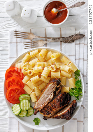 Fried pork ribs with pasta and fresh vegetables 135797742