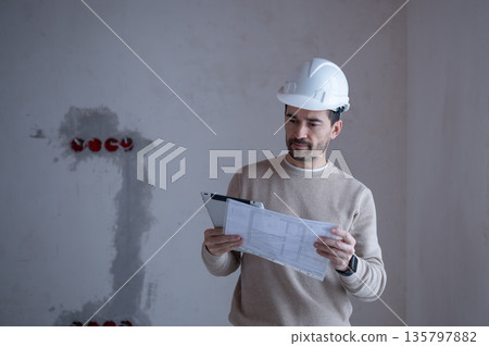 Construction site supervisor reviewing blueprints and using digital tablet Construction site supervisor reviewing blueprints and using digital tablet 135797882