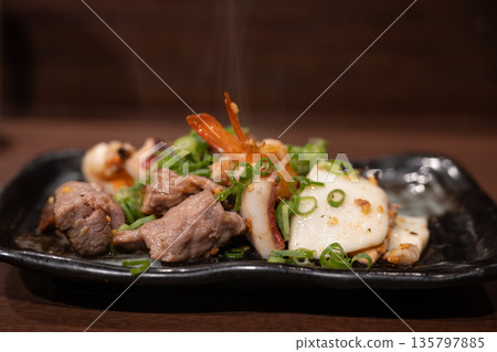 Steaming hot surf and turf with beef, shrimp and squid, garnished with chopped green onions Steaming hot surf and turf with beef, shrimp and squid, garnished with chopped green onions 135797885