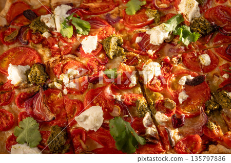 Delicious homemade pizza with tomatoes, ricotta, pesto and coriander is cut into square slices 135797886