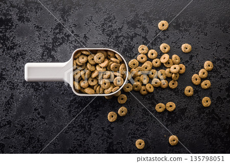 Dry kibble pet food. Dog or cat food in scoop on black table. Top view. 135798051