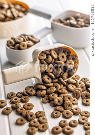 Dry kibble pet food. Dog or cat food in scoop on white table. 135798053