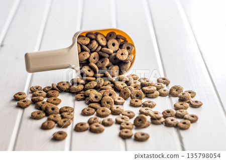 Dry kibble pet food. Dog or cat food in scoop on white table. Dry kibble pet food. Dog or cat food in scoop on white table. 135798054