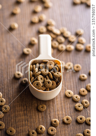 Dry kibble pet food. Dog or cat food in scoop on wooden table. Dry kibble pet food. Dog or cat food in scoop on wooden table. 135798057