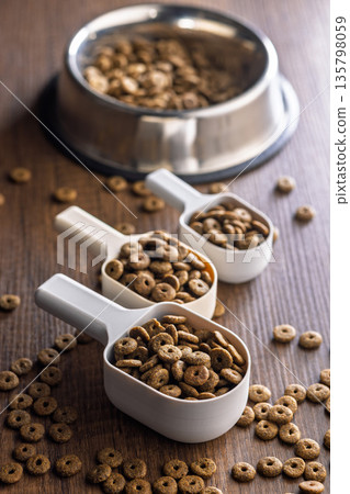 Dry kibble pet food. Dog or cat food in scoop on wooden table. 135798059