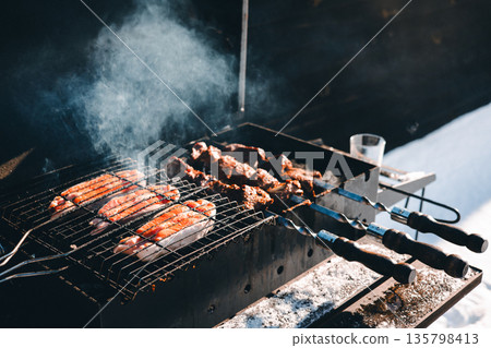 A candid winter barbecue moment, authentic human storytelling. Preparing shashlik skewers, steaks over hot coals, outdoor cooking. Weekend leisure. A candid winter barbecue moment, authentic human storytelling. Preparing shashlik skewers, steaks over hot coals, outdoor cooking. Weekend leisure. 135798413
