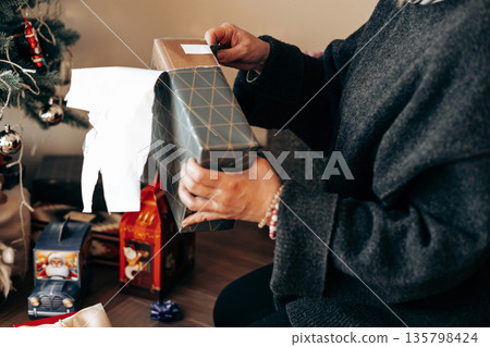 A candid, real-life moment of unwrapping gifts, capturing authentic human storytelling and the cozy 'Ambient Realism' aesthetic Festive winter holiday 135798424