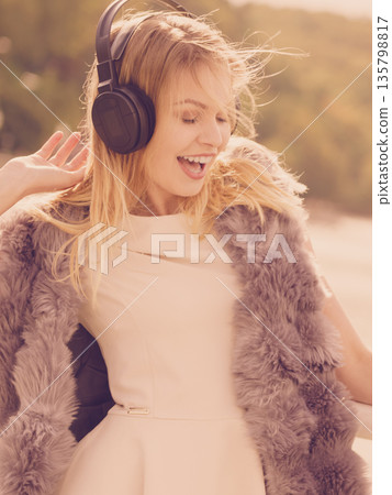 Happy woman wearing headphones outdoor 135798817