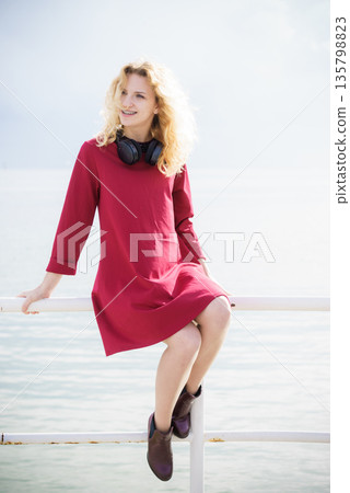 Woman wearing red dress and headphones Woman wearing red dress and headphones 135798823