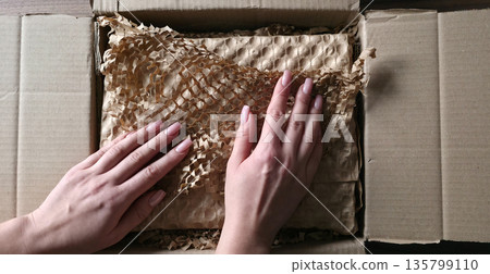 A woman is holding an eco-friendly paper package. Packaging goods in paper packaging. Careful and eco-friendly production and delivery of goods. High quality photo A woman is holding an eco-friendly paper package. Packaging goods in paper packaging. Careful and eco-friendly production and delivery of goods. High quality photo 135799110