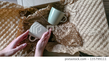 A woman is holding an eco-friendly paper package. Packaging goods in paper packaging. Careful and eco-friendly production and delivery of goods. High quality photo 135799111