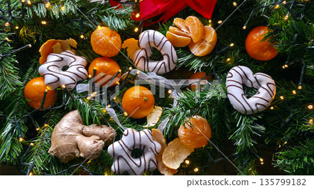 Tangerines, gingerbread, and a string of lights on fir branches. decorations and ornaments for the New Year. the festive atmosphere of Christmas and New Year. High quality photo Tangerines, gingerbread, and a string of lights on fir branches. decorations and ornaments for the New Year. the festive atmosphere of Christmas and New Year. High quality photo 135799182