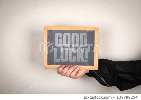 GOOD LUCK Message On Chalkboard Held By Hand Against Neutral Background GOOD LUCK Message On Chalkboard Held By Hand Against Neutral Background 135799254