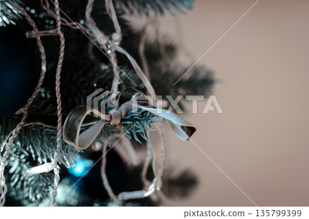 An artificial Christmas fir tree decorated with simple blue ribbon. Cozy seasonal content and winter holiday decor. 135799399