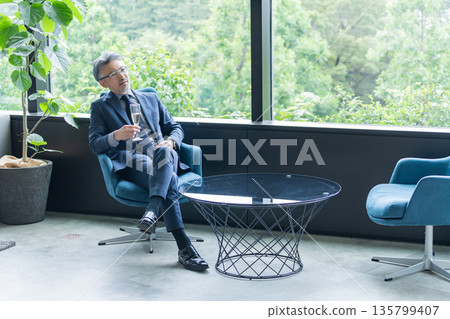 Middle-aged businessman drinking alcohol at a dinner party Middle-aged businessman drinking alcohol at a dinner party 135799407
