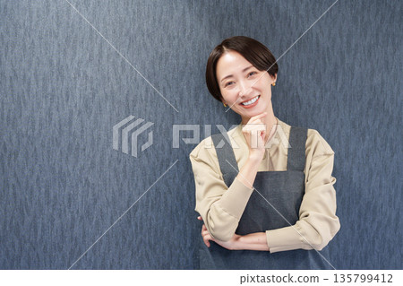 一位穿著圍裙、正在思考的女職員 135799412