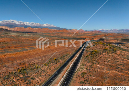 Aerial highway in red desert with snowy mountains Mesquite Nevada Aerial highway in red desert with snowy mountains Mesquite Nevada 135800030
