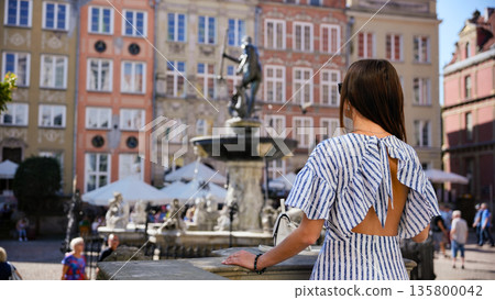 Tourist woman looking at fountain on Long Market square in Gdansk Poland 135800042