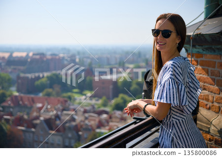 Woman on rooftop balcony overlooking Gdansk old town panorama Woman on rooftop balcony overlooking Gdansk old town panorama 135800086