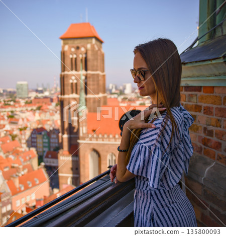 Woman on rooftop viewpoint with camera overlooking Gdansk old town markdown 135800093