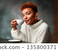 Young black woman drinking coffee or tea from a white cup, , embodying calm and relaxation in minimalist interior 135800371