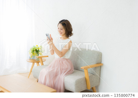 A smiling woman looking at a smartphone A smiling woman looking at a smartphone 135800774
