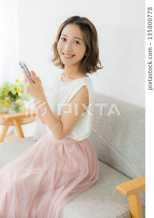 A smiling woman looking at a smartphone 135800778