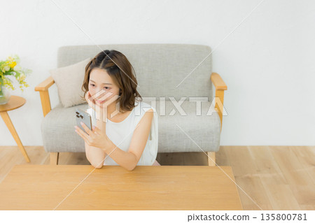 一個微笑的女人看著智能手機 135800781