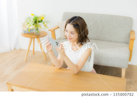 一個微笑的女人看著智能手機 135800782