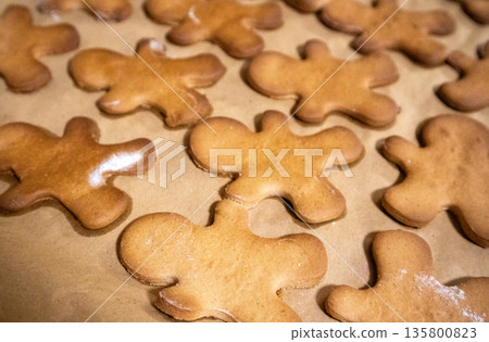 Homemade gingerbread men cookies cooling on baking paper close-up, warm-toned shot. Classic Christmas holiday treats, popular for festive appeal, perfect for seasonal, winter, food-related themes. Homemade gingerbread men cookies cooling on baking paper close-up, warm-toned shot. Classic Christmas holiday treats, popular for festive appeal, perfect for seasonal, winter, food-related themes. 135800823