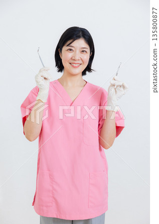 Smiling dental hygienist holding a toothbrush Smiling dental hygienist holding a toothbrush 135800877