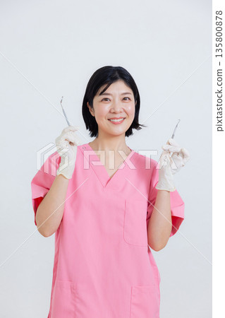 Smiling dental hygienist holding a toothbrush Smiling dental hygienist holding a toothbrush 135800878